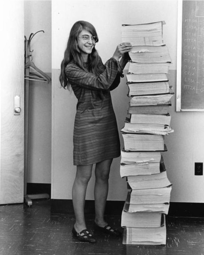 Margaret Hamilton standing next to a colossal stack of papers